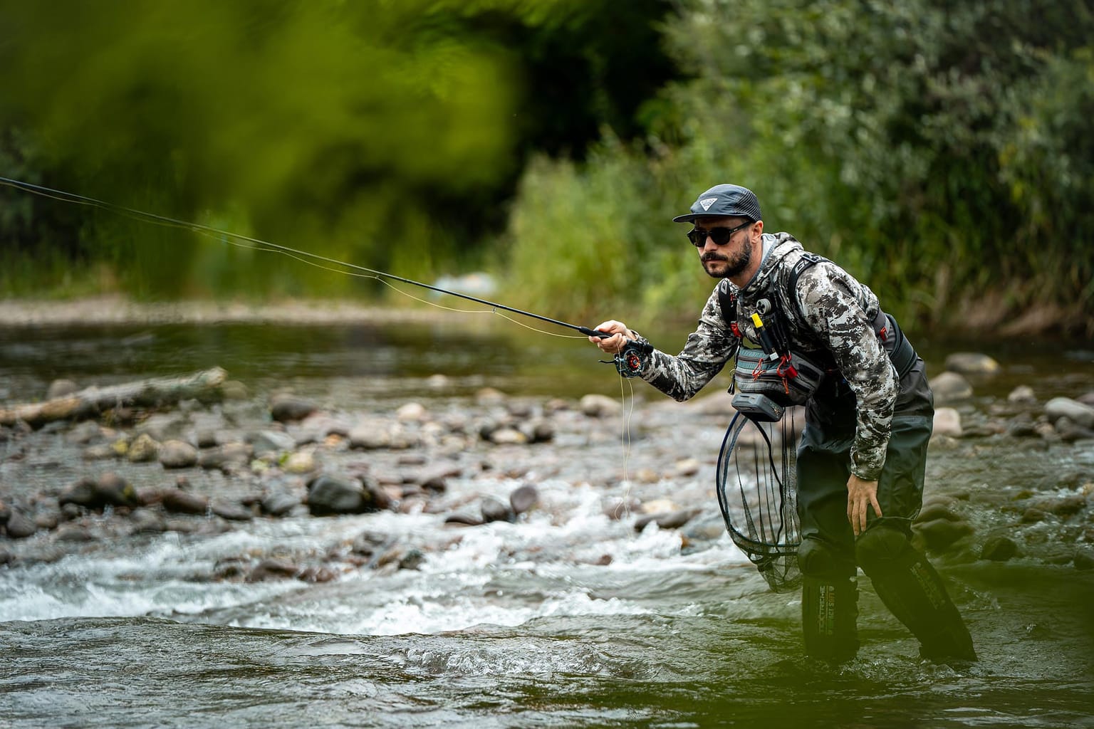 Guida di pesca a mosca durante un lancio in un fiume alpino delle Dolomiti